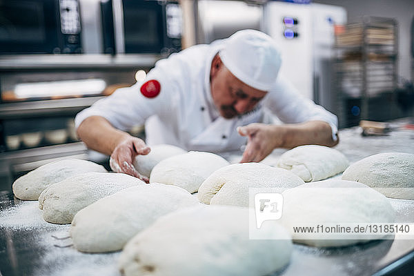 Baker working with dough in bakery