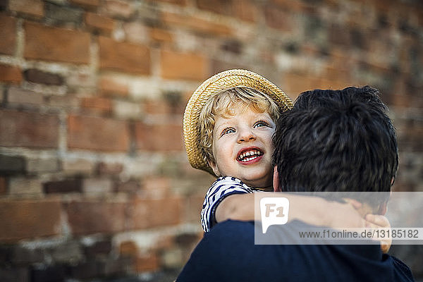 Porträt eines glücklichen Kleinkindes auf den Armen seines Vaters