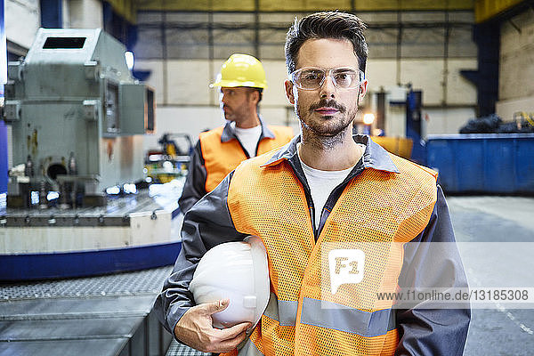 Porträt eines seriösen Mannes mit Arbeitsschutzkleidung in einer Fabrik