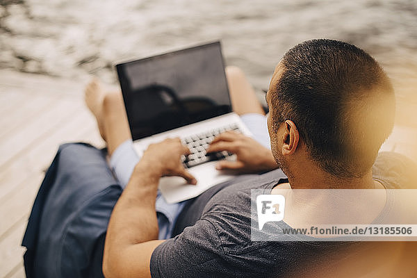 Hochwinkelansicht eines reifen Mannes mit Laptop bei der Arbeit im Sommerurlaub
