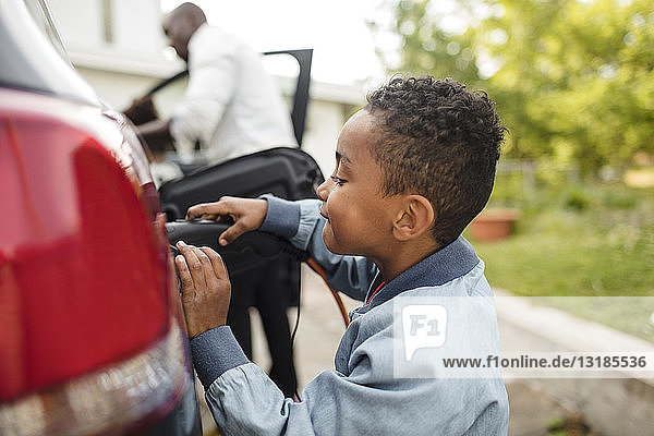 Side view of boy looking while charging electric car