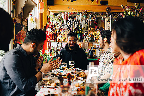 Fröhliche junge multi-ethnische Freunde genießen Brunch  während sie im Restaurant am Tisch sitzen