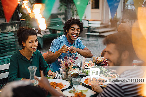 Cheerful male and female friends enjoying during dinner party in backyard
