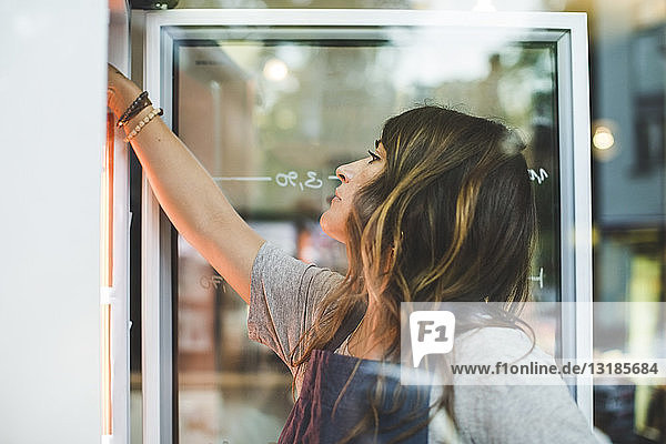 Weibliche Angestellte sucht im Kühlschrank eines Feinkostladens