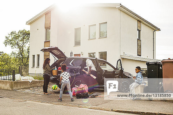 Familie mit Elektroauto auf Einfahrt gegen Haus