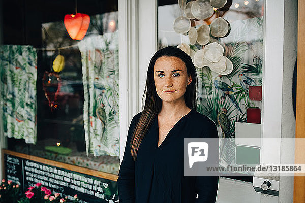 Porträt einer selbstbewussten jungen Frau  die gegen ein Restaurant steht