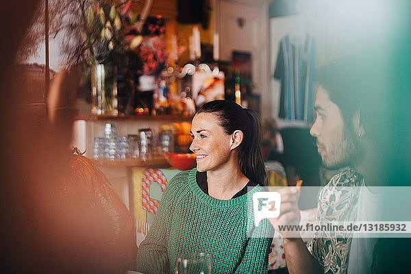 Happy young male and female friends sitting in restaurant during dinner party