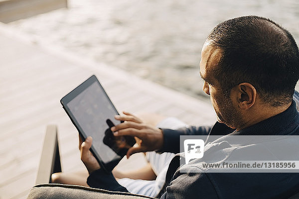 Hochwinkelansicht eines Mannes mit digitalem Tablett auf der Terrasse am See