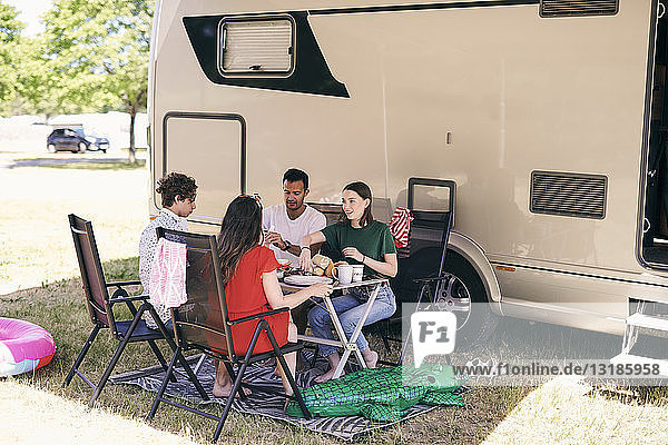 Familienmitglieder in voller Länge  die beim Zelten auf einem Wohnwagenpark Lebensmittel gegen einen Lieferwagen erhalten
