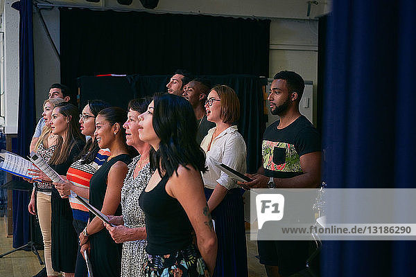 Multi-ethnische Gruppe von Schülern  die im Chor in der Schulaula singen