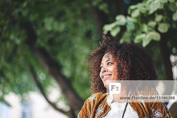 Nahaufnahme einer nachdenklichen Frau mittleren Alters mit lockigem Haar  die auf den Park schaut