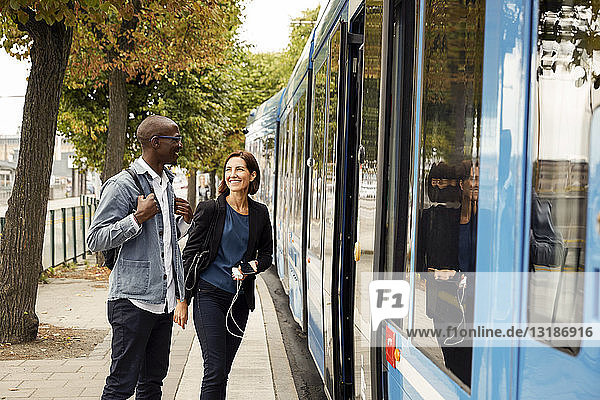 Smiling multi-ethnic commuters standing by blue tram in city