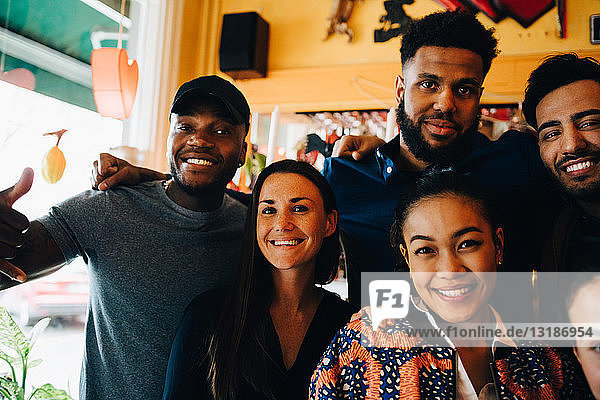 Porträt lächelnder junger multiethnischer Freunde beim Stehen im Restaurant während des Brunch