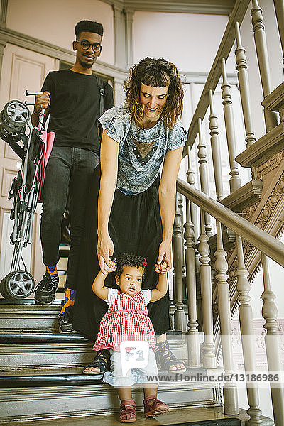 Mutter hält die Hände einer Tochter  die auf einer Treppe in einer Wohnung nach unten geht