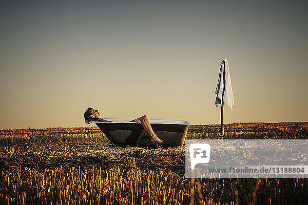 Frau entspannt sich in einer Badewanne in einem ländlichen Gebiet