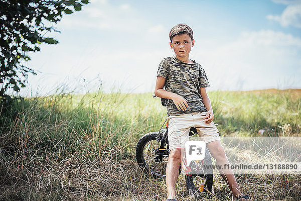 Portrait confident boy on bicycle in rural field