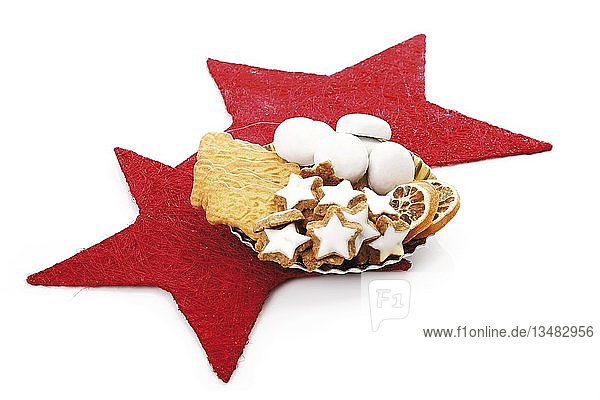 Plate of assortmed christmas biscuits on red stars decoration  cinnamon star-shaped biscuits  spiced biscuits  gingerbread biscuits and dried orange slices