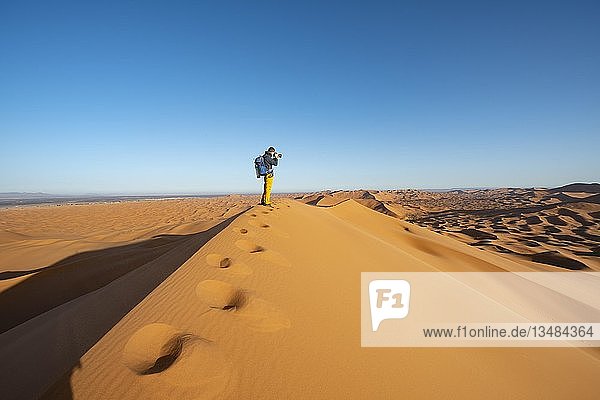 Junger Mann steht auf einer Sanddüne und wird fotografiert  Erg Chebbi  Merzouga  Sahara  Marokko  Afrika