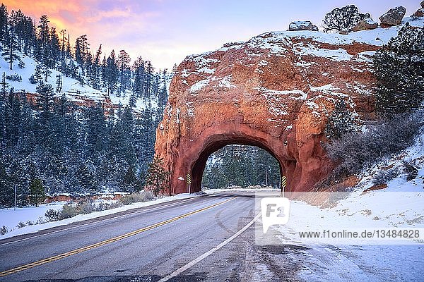 Straße mit Tunnel durch roten Felsbogen im Schnee  bei Sonnenuntergang  Highway 12  Sandsteinfelsen  Red Canyon  Panguitch  Utah  USA  Nordamerika