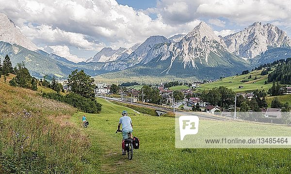 Cyclist on bike tour with mountain bike  on the cycle path Via Claudia Augusta  in the back Ehrwalder Sonnenspitze  crossing the Alps  mountain landscape  Alps  Ehrwald Basin  near Ehrwald  Tyrol  Austria  Europe