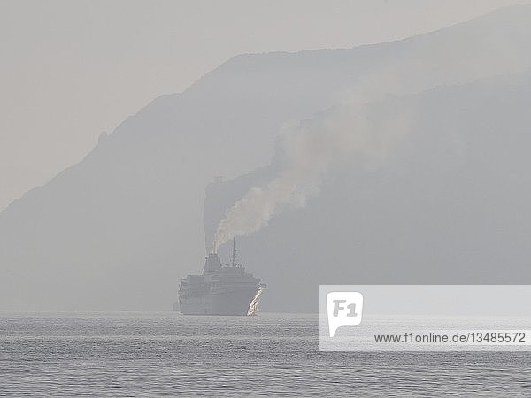 Kreuzfahrtschiff mit rauchendem Schlot im Morgennebel im Golf von Neapel bei Sorrento  Kampanien  Italien  Europa