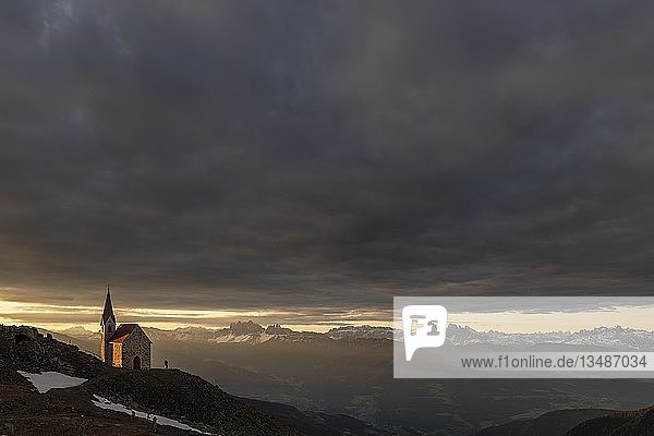 Latzfonser Kreuzkapelle bei Sonnenaufgang mit dramatischen Wolken und Südtiroler Bergen  Sarntaler Alpen  San Martino  Sarntal  Südtirol  Italien  Europa