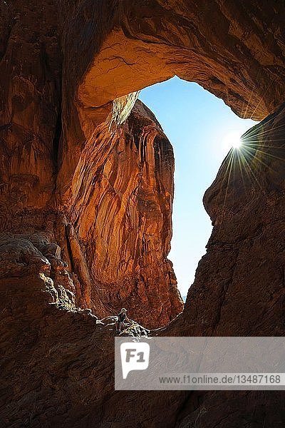Wanderer entspannt sich unter dem Double Arch  Steinbögen aus rotem Sandstein  die durch Erosion entstanden sind  Arches-Nationalpark  in der Nähe von Moab  Utah  Vereinigte Staaten  Nordamerika