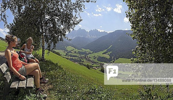 Hikers resting above S. Magdalena on the Bergbauernweg trail  Villnoesstal valley  province of Bolzano-Bozen  Italy  Europe