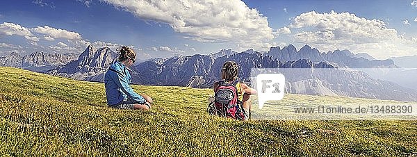 Hikers sitting on Aferer Alm alp on Plosen mountain  view of Aferer Geisler Massif and Peitlerkofel mountain  Wuerzjoch ridge  Villnoesstal valley  Dolomites  province of Bolzano-Bozen  Italy  Europe