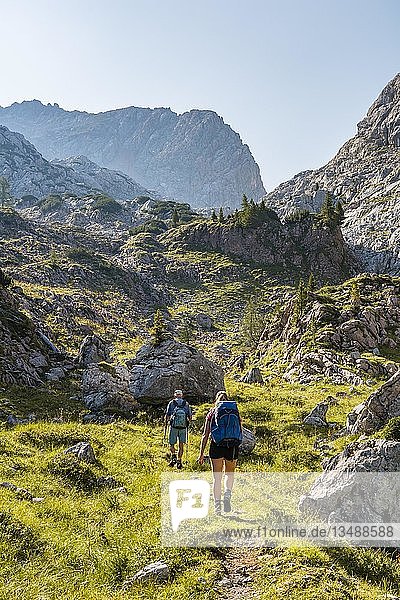 Two hikers on one hiking trail  mountain landscape  Stuhlgraben  Hinterten GrieÃŸkogel  Steinernes Meer  Funtenseetauern  National Park Berchtesgaden  Berchtesgadener Land  Upper Bavaria  Bavaria  Germany  Europe