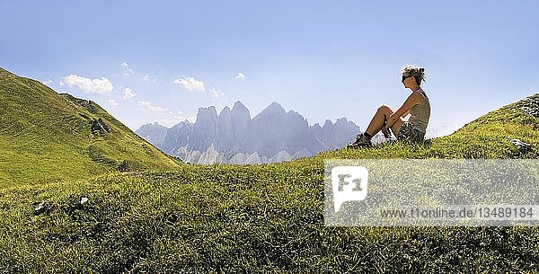 Girl relaxing in a meadow enjoying the view of the Geisler group  Aferer Geisler mountains  Villnoesstal valley  province of Bolzano-Bozen  Italy  Europe