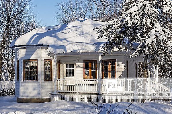 Alte  mit weißen Holzplanken verkleidete Hausfassade mit braunen Zierleisten und blauem Blechdach im Winter  Quebec  Kanada  Nordamerika