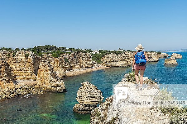 Young woman standing on rocks  view over turquoise sea  beach Praia da Marinha  rugged rocky coast of sandstone  rock formations in the sea  Algarve  Lagos  Portugal  Europe