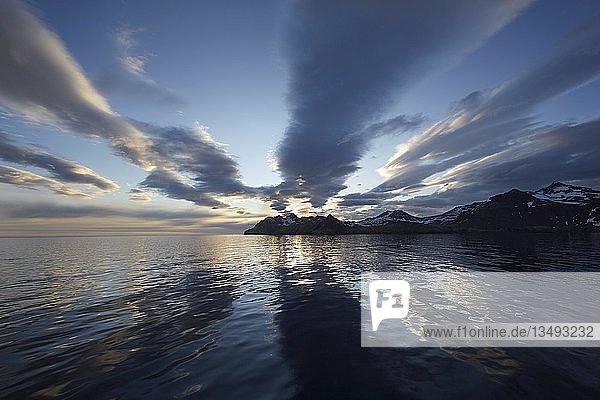 Sonnenaufgang in Stromness mit Wolkenformationen und Spiegelungen in der Bucht  hinter der Küste mit Bergspitzen  Stromness Bay  Südgeorgien  Vereinigtes Königreich  Europa
