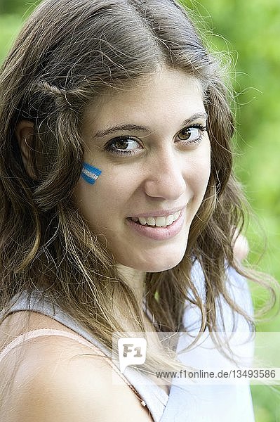 Porträt einer jungen Argentinierin mit der argentinischen Flagge auf der Wange