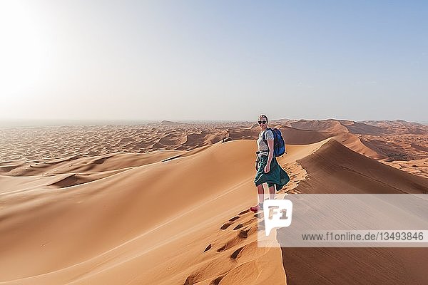 Female hiker on a red sand dune in the desert  dune landscape Erg Chebbi  Merzouga  Sahara  Morocco  Africa