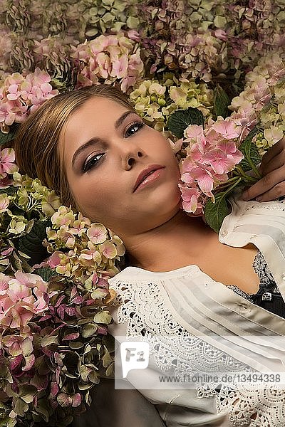 Woman lies in a sea of flowers  portrait  look into the camera