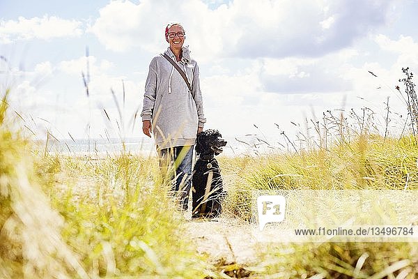 Frau geht mit ihrem Hund  Königspudel  in den Dünen am Meer spazieren  Portbail  Normandie  Frankreich  Europa