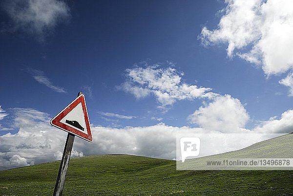 Straßenschild  das vor einer holprigen Straße warnt  vor einem grünen Hügel unter einem blauen Himmel  Campo Imperatore  Abruzzen  Italien  Europa