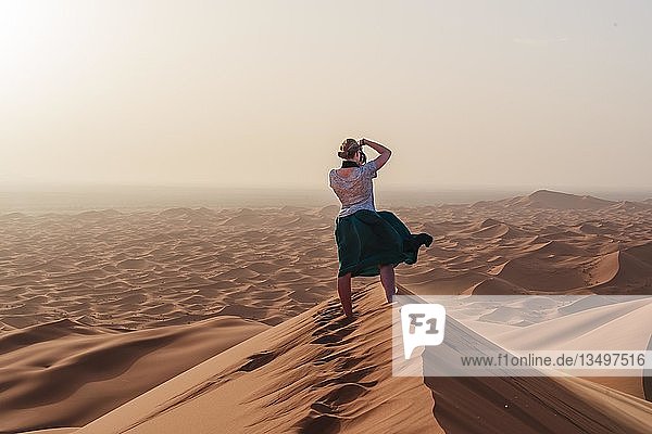 Junge Frau beim Fotografieren in der Ferne  rote Sanddüne in der Wüste  Dünenlandschaft Erg Chebbi  Merzouga  Sahara  Marokko  Afrika