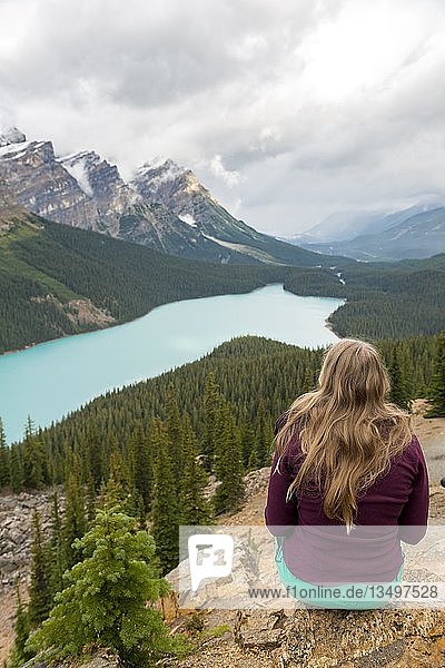 Young woman sitting on a stone looking into nature  turquoise lake  Peyto Lake  Rocky Mountains  Banff National Park  Alberta Province  Canada  North America