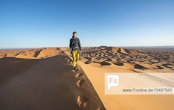 Junger Mann läuft auf Sanddüne  Erg Chebbi  Merzouga  Sahara  Marokko  Afrika