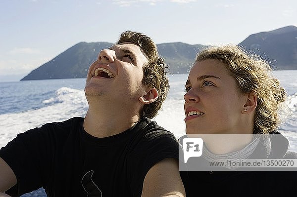 Junges Paar sitzt am Heck eines kleinen Bootes  Isola Eolie  Sizilien  Italien  Europa