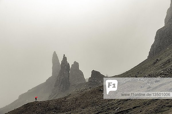Rock Old Man of Storr with tourist with red umbrella in fog  Portree  Isle of Sky  Scotland  Great Britain