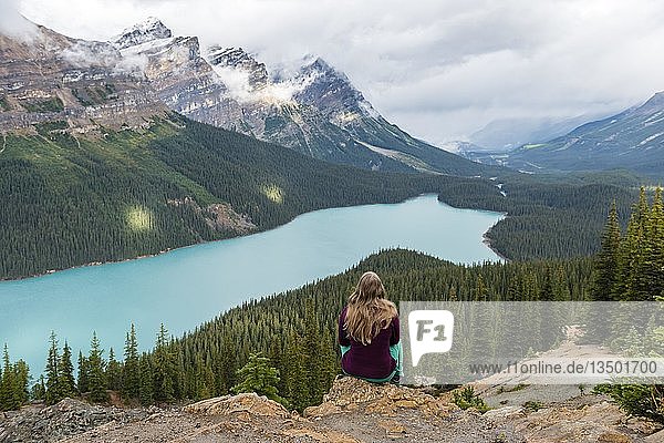 Young woman sitting on a stone looking into nature  turquoise lake  Peyto Lake  Rocky Mountains  Banff National Park  Alberta Province  Canada  North America
