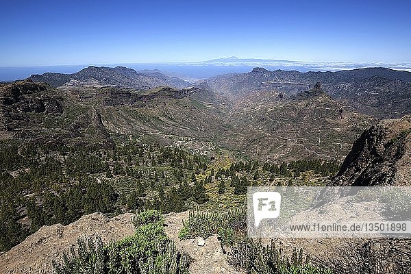 Blick vom Roque Nublo  Kultfelsen der Altkanarier  in den Barranco del Chorrillo und die Berge im Westen von Gran Canaria  hinter Teneriffa mit dem Vulkan Teide  rechts hinten der Kultfelsen Roque Bentayga  Gran Canaria  Kanarische Inseln  Spanien  Europa