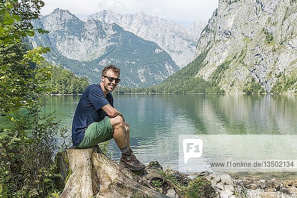 Junger Wanderer sitzt am Ufer des Obersees  hinter dem Watzmann  Nationalpark Berchtesgaden  Berchtesgadener Land  Oberbayern  Bayern  Deutschland  Europa