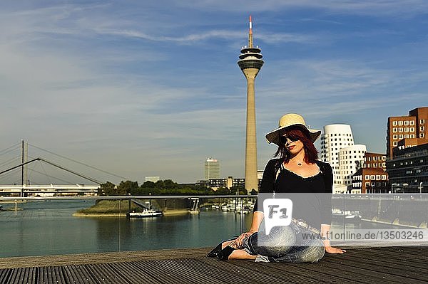 Junge Frau vor der Kulisse des Medienhafens in der Abendsonne Düsseldorf Nordrhein-Westfalen Deutschland Europa