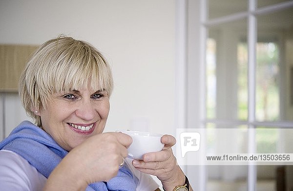 Eine Frau sitzt in ihrem Büro und trinkt aus einer Tasse Tee