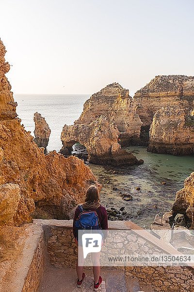 Female hiker looks over rocks in the sea  Algarve rocky coast  Ponta da Piedade  Lagos  Portugal  Europe